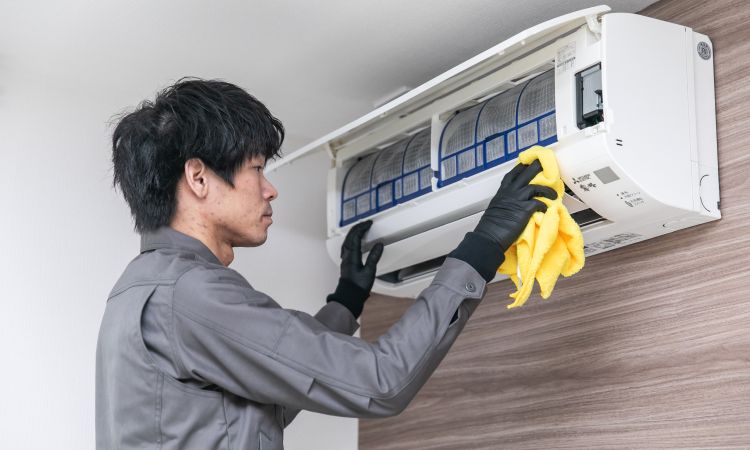 エアコンクリーニング作業中のスタッフ、内部フィルターを清掃しカビや汚れを除去する様子（名古屋対応）