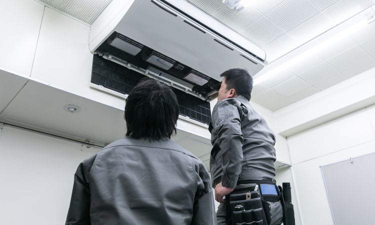 業務用エアコンクリーニングを行うスタッフ2名、天井埋込型エアコンを分解清掃する作業風景（累計2万台の実績）