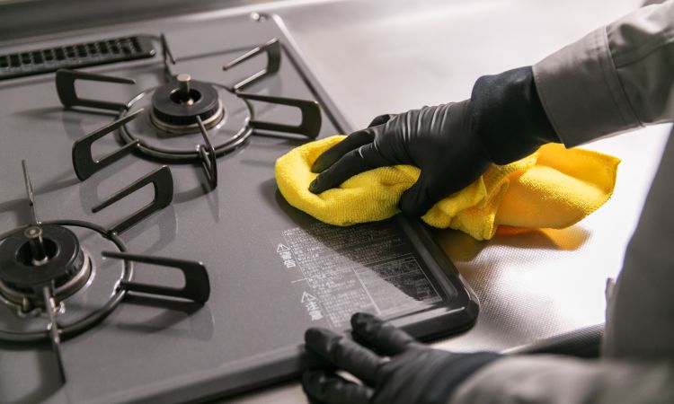 キッチンクリーニングでコンロやシンクの油汚れを専用洗剤で清掃する作業風景