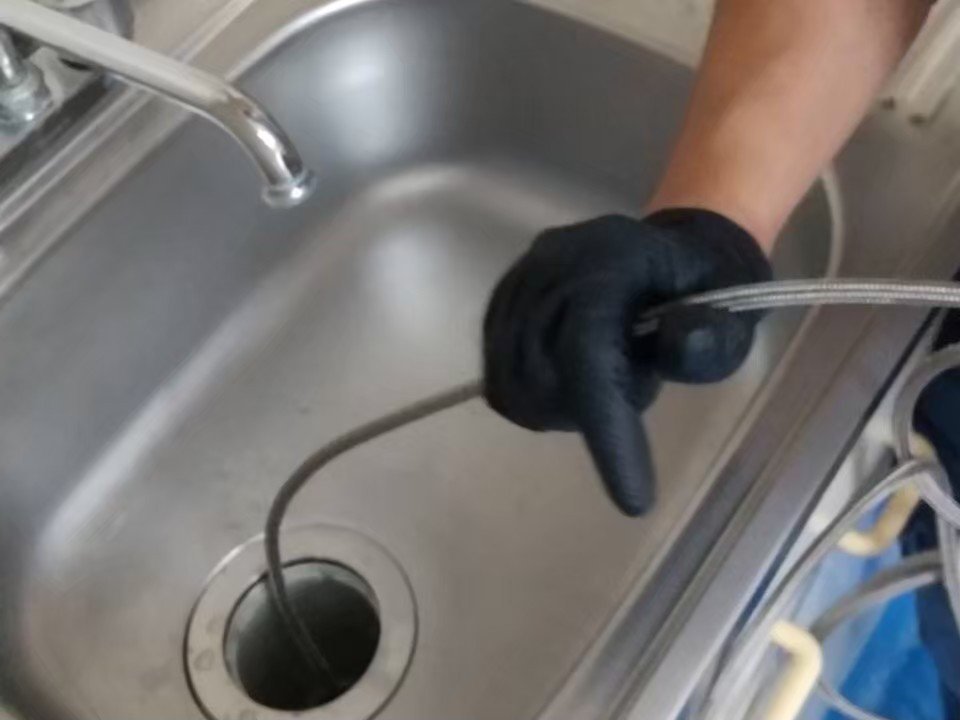 排水口の内部を専用の道具で洗浄している作業中の様子
